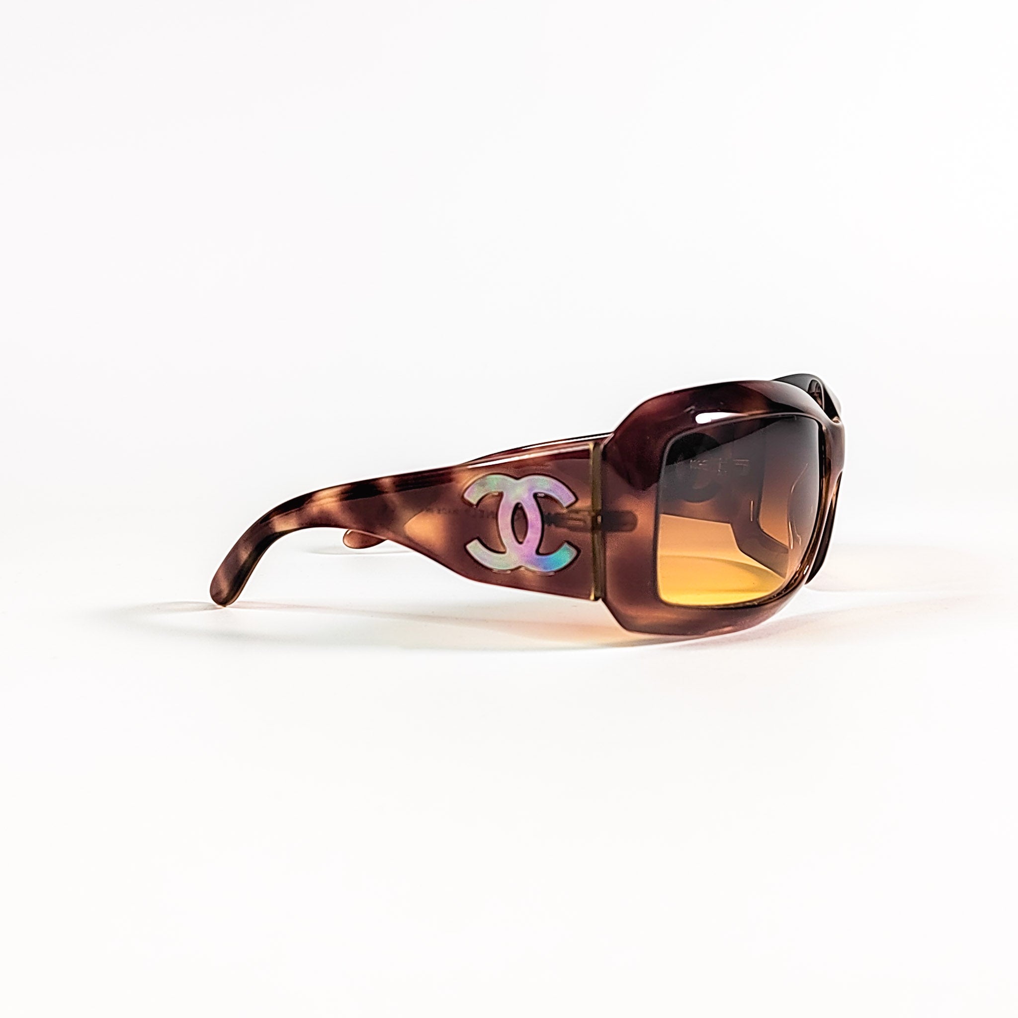 Chanel 5076-H vue trois-quarts, branche écaille avec logo CC incrusté de nacre irisée rose et vert.